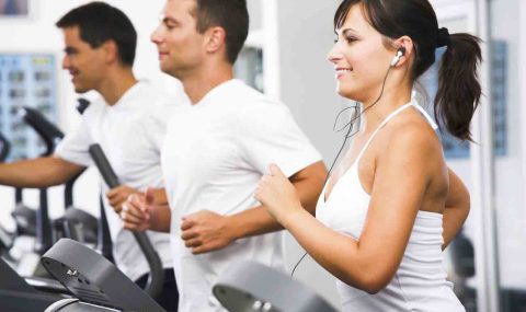 Young adults using running machine at the fitness club